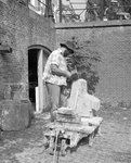 880861 Afbeelding van een beeldhouwer aan het werk op de werf langs de Nieuwegracht bij de Quintijnsbrug te Utrecht, ...
